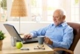 8748721-smiling-senior-man-using-laptop-typing-on-keyboard-holding-coffee-mug-at-home